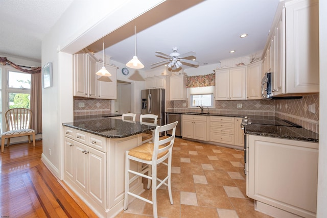 14 N Cambridge Ave, Ventnor, NJ 08406 - kitchen with stainless steel appliances, a breakfast bar, a baseboard heating unit, decorative backsplash, and dark stone counters