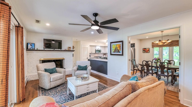 9 Lesley Ln, Northfield, NJ 08225 - living area featuring wood finished floors, a chandelier, a brick fireplace, ceiling fan, and ornamental molding