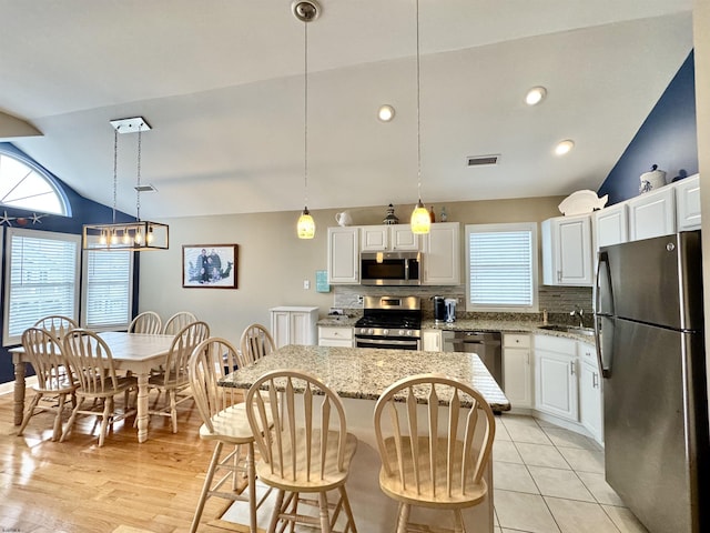 331 Asbury Ave Unit 2, Ocean City, NJ 08226 - kitchen featuring appliances with stainless steel finishes, lofted ceiling, tasteful backsplash, a kitchen island, and white cabinetry