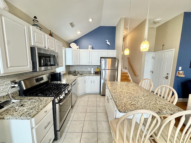 331 Asbury Ave Unit 2, Ocean City, NJ 08226 - kitchen with stainless steel appliances, tasteful backsplash, a kitchen bar, light stone counters, and high vaulted ceiling