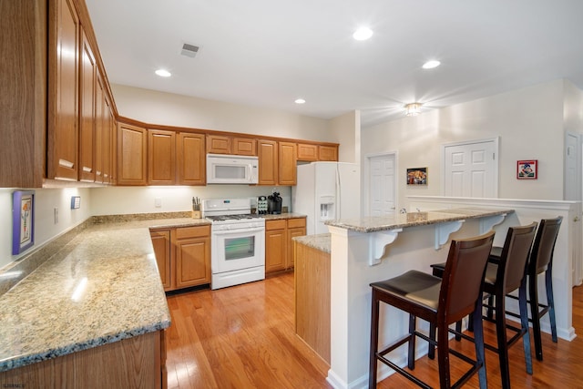 11 Brampton St, Galloway Township, NJ 08205 - kitchen featuring white appliances, light wood-type flooring, a kitchen bar, recessed lighting, and light stone countertops