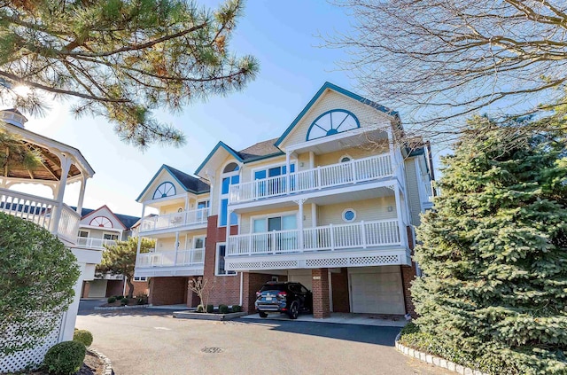 122 S Pointe Unit 122, Somers Point, NJ 08244 - view of front facade with brick siding, a carport, a balcony, asphalt driveway, and an attached garage