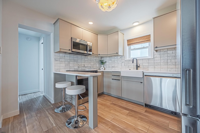 3801 Ocean Ave Unit 2, Brigantine, NJ 08203 - kitchen featuring stainless steel appliances, light countertops, light wood finished floors, decorative backsplash, and a kitchen breakfast bar