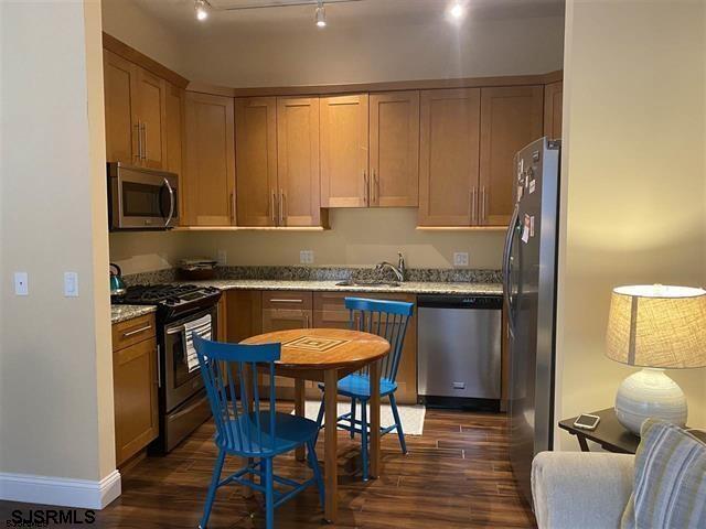1 Mechanic St Unit 108, Absecon, NJ 08201 - kitchen featuring stainless steel appliances, dark wood finished floors, rail lighting, and light stone countertops
