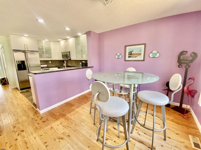 24 Coquille Beach Dr Unit 24, Brigantine, NJ 08203 - kitchen with appliances with stainless steel finishes, dark countertops, a peninsula, light wood finished floors, and white cabinets