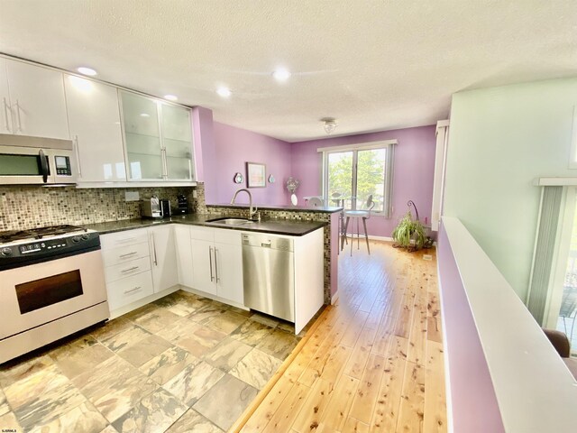 24 Coquille Beach Dr Unit 24, Brigantine, NJ 08203 - kitchen with stainless steel appliances, a peninsula, dark countertops, tasteful backsplash, and white cabinetry