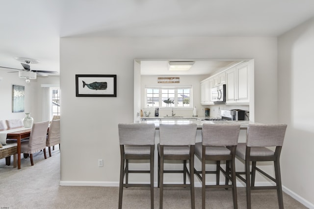 417 Albacore Ln, Brigantine, NJ 08203 - kitchen with stainless steel microwave, a breakfast bar area, range, white cabinets, and a peninsula
