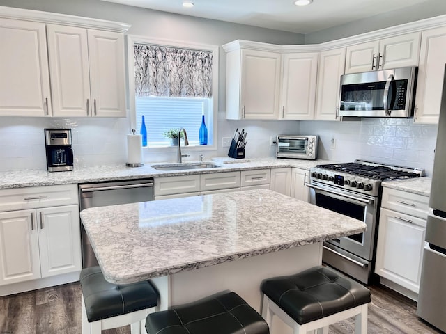 1304 Roberts Ave, Somers Point, NJ 08244 - kitchen with appliances with stainless steel finishes, a breakfast bar, white cabinetry, dark wood-type flooring, and recessed lighting