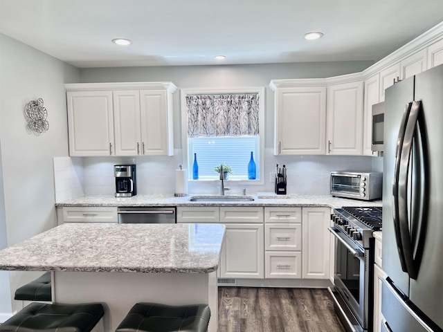 1304 Roberts Ave, Somers Point, NJ 08244 - kitchen featuring appliances with stainless steel finishes, a breakfast bar area, dark wood-style flooring, white cabinets, and tasteful backsplash