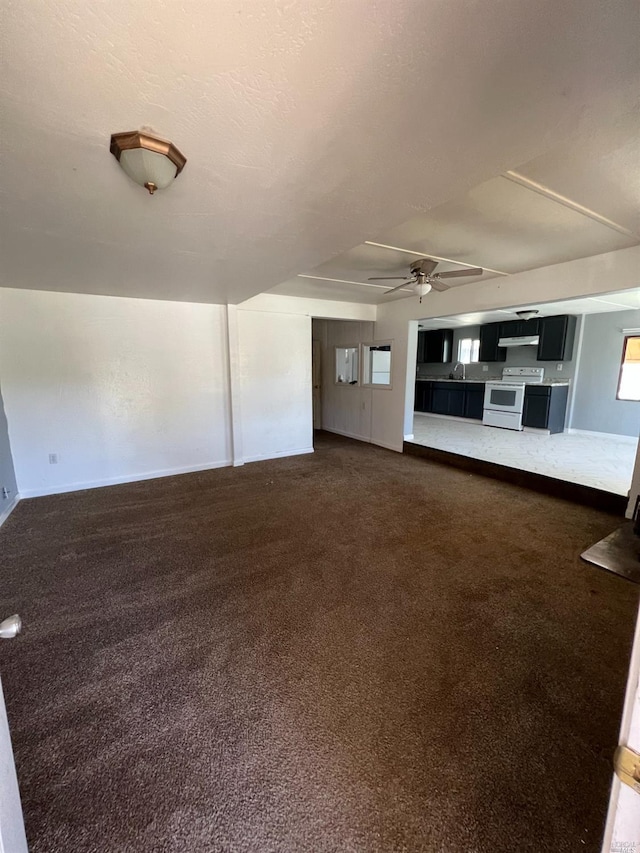 unfurnished living room featuring ceiling fan, dark colored carpet, and sink