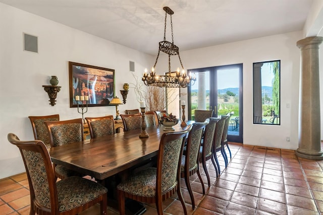 dining room featuring dark tile floors, an inviting chandelier, and decorative columns