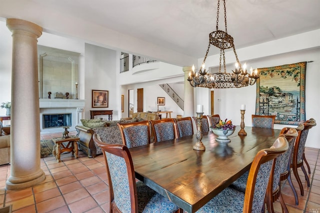 dining area with light tile floors, decorative columns, a large fireplace, and a notable chandelier