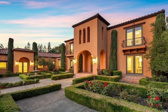 mediterranean / spanish house featuring a balcony and french doors