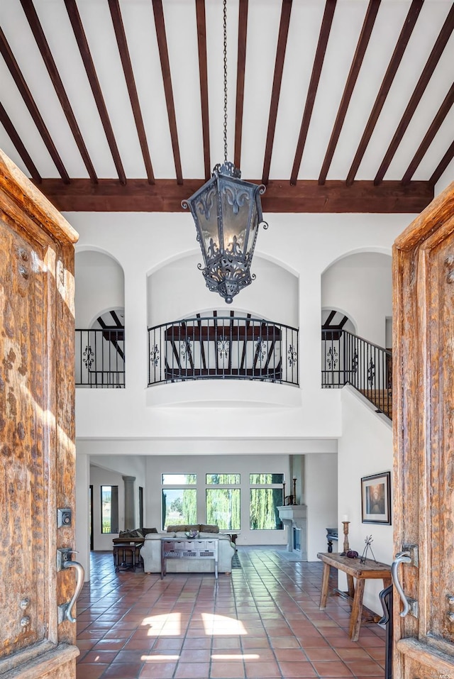 interior space with beam ceiling, high vaulted ceiling, an inviting chandelier, and tile flooring