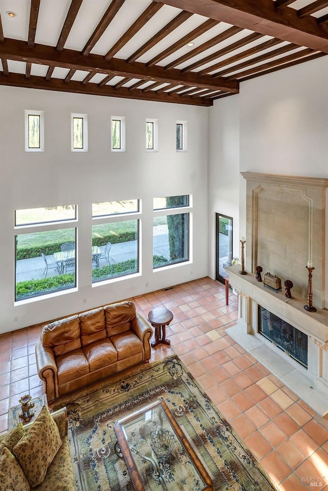 unfurnished living room featuring a tiled fireplace, beam ceiling, and light tile floors