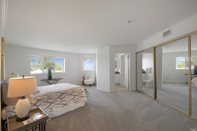 bedroom featuring crown molding, a closet, light colored carpet, and ensuite bathroom