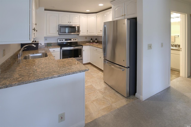 kitchen featuring light tile flooring, sink, stainless steel appliances, white cabinets, and dark stone counters