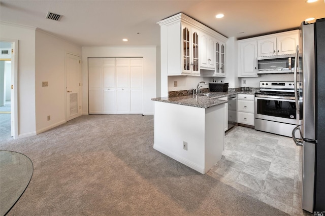 kitchen featuring white cabinetry, sink, stainless steel appliances, dark stone countertops, and ornamental molding