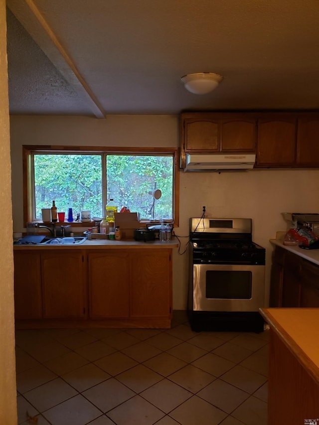 kitchen with light tile flooring, stainless steel gas range, and sink