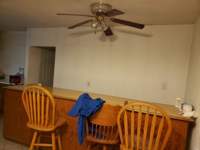 tiled dining area featuring ceiling fan and a textured ceiling