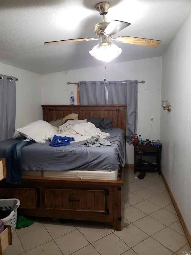 bedroom featuring a textured ceiling, ceiling fan, and light tile floors