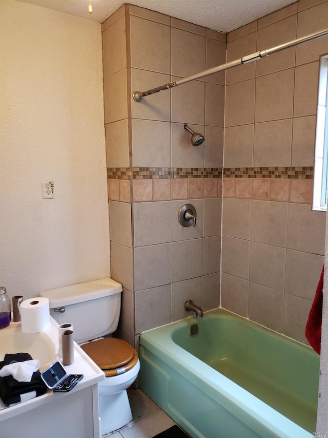 bathroom featuring tile flooring, a textured ceiling, toilet, and tiled shower / bath