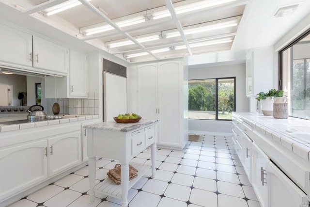 kitchen with light tile floors, white cabinets, tasteful backsplash, and tile countertops