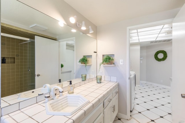 bathroom with tile floors, vanity with extensive cabinet space, and washing machine and clothes dryer