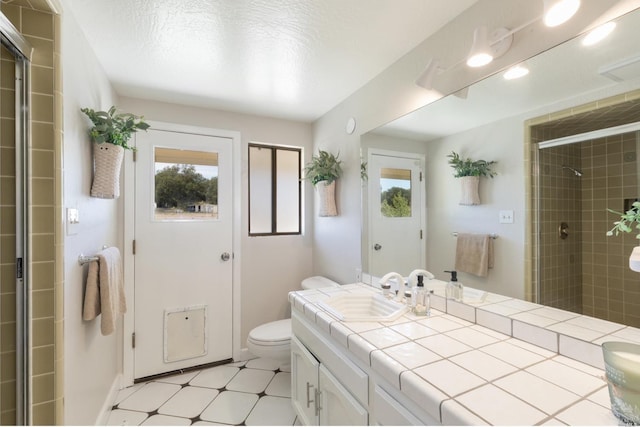 bathroom with tile floors, toilet, large vanity, and an enclosed shower