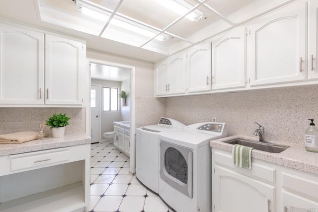 laundry area with washer and clothes dryer, cabinets, sink, and light tile floors