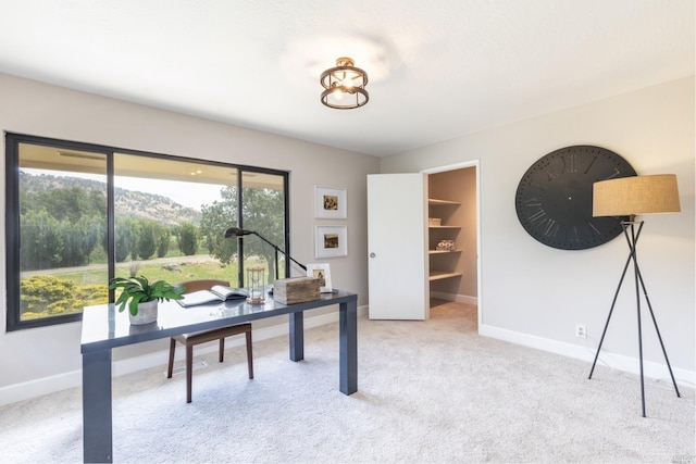 home office with a mountain view, light carpet, and a healthy amount of sunlight