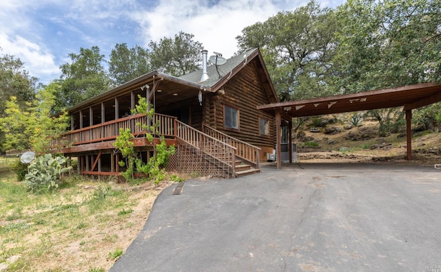 view of front of home featuring log siding, aphalt driveway, and stairway