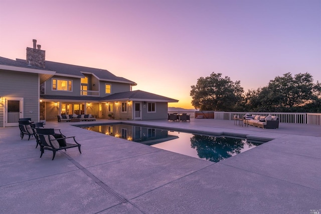 pool at dusk featuring a patio