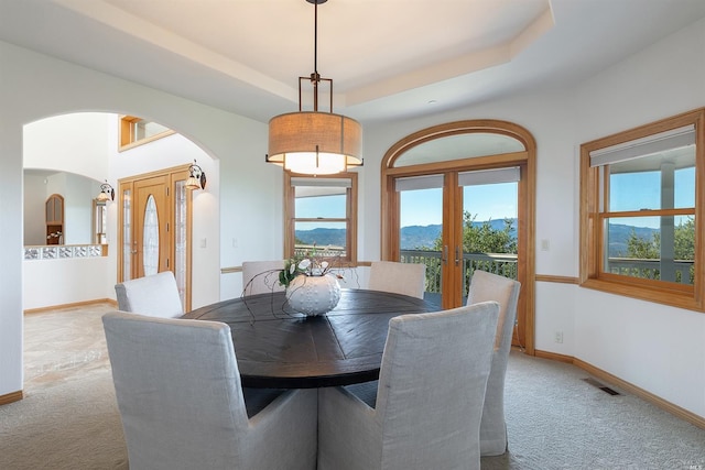 carpeted dining room featuring a tray ceiling and french doors