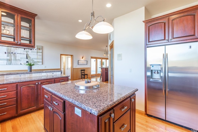 kitchen with stainless steel fridge with ice dispenser, decorative light fixtures, a center island, and light wood-type flooring