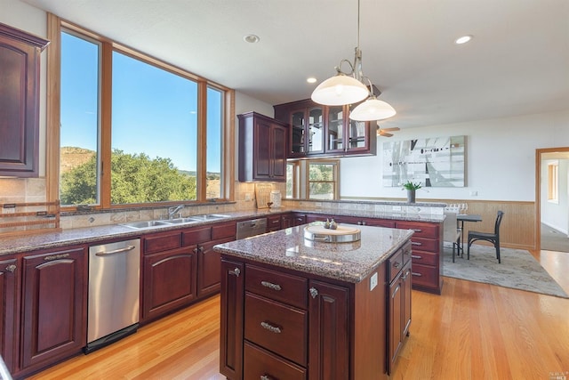 kitchen featuring a kitchen island, stainless steel dishwasher, light hardwood / wood-style floors, and pendant lighting