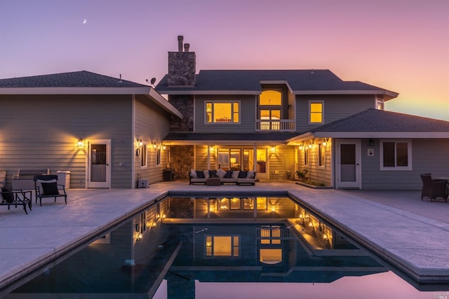 pool at dusk with a patio area and an outdoor living space