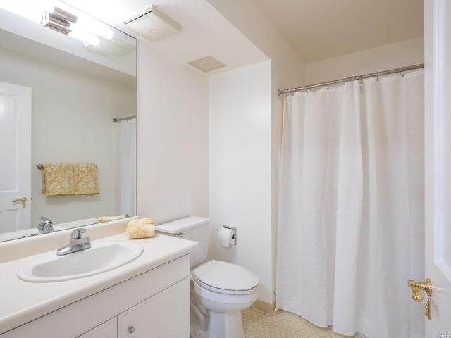 bathroom featuring tile flooring, toilet, and vanity with extensive cabinet space