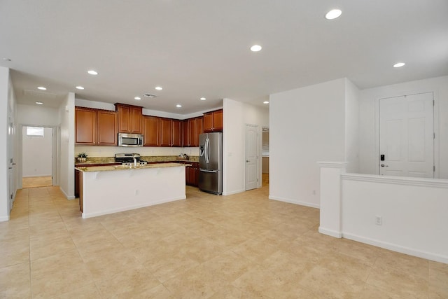 kitchen with a kitchen island with sink, light stone counters, a kitchen breakfast bar, appliances with stainless steel finishes, and light tile flooring