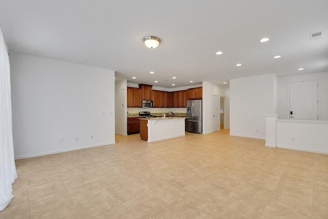 kitchen with light tile flooring, an island with sink, and appliances with stainless steel finishes