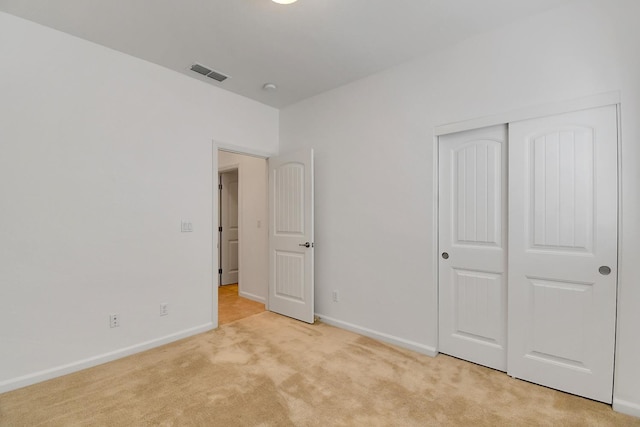 unfurnished bedroom featuring a closet and light colored carpet