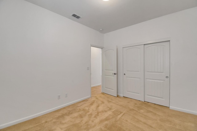 unfurnished bedroom featuring a closet and light carpet