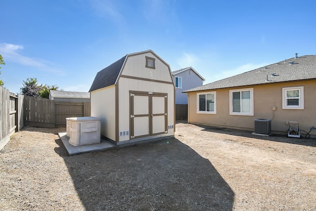 rear view of property with central AC unit and a storage unit