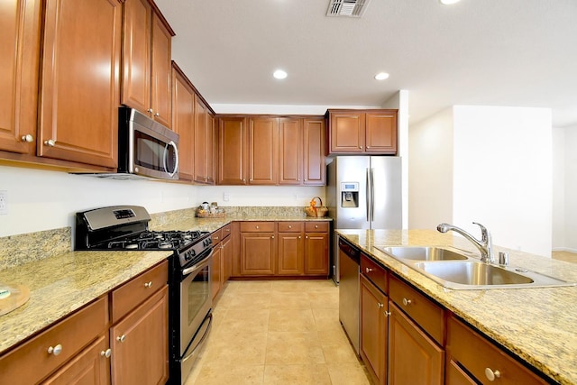 kitchen featuring stainless steel appliances, sink, light tile floors, and light stone countertops