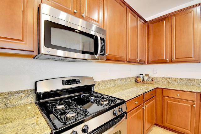 kitchen with light tile floors, stainless steel appliances, and light stone countertops