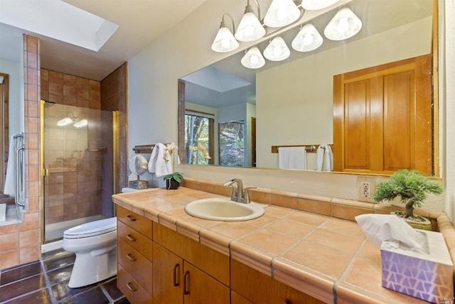 bathroom with toilet, large vanity, a skylight, a shower with door, and tile floors