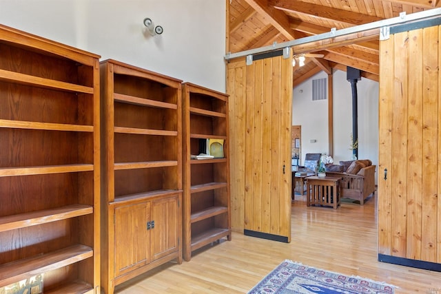 spacious closet featuring a barn door, light wood-type flooring, and lofted ceiling with beams