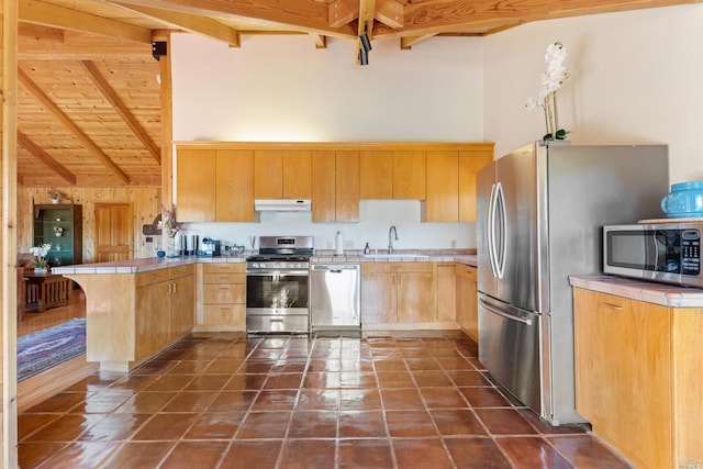 kitchen with light brown cabinets, appliances with stainless steel finishes, dark tile floors, sink, and beam ceiling