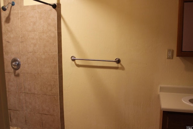 bathroom featuring tiled shower and vanity