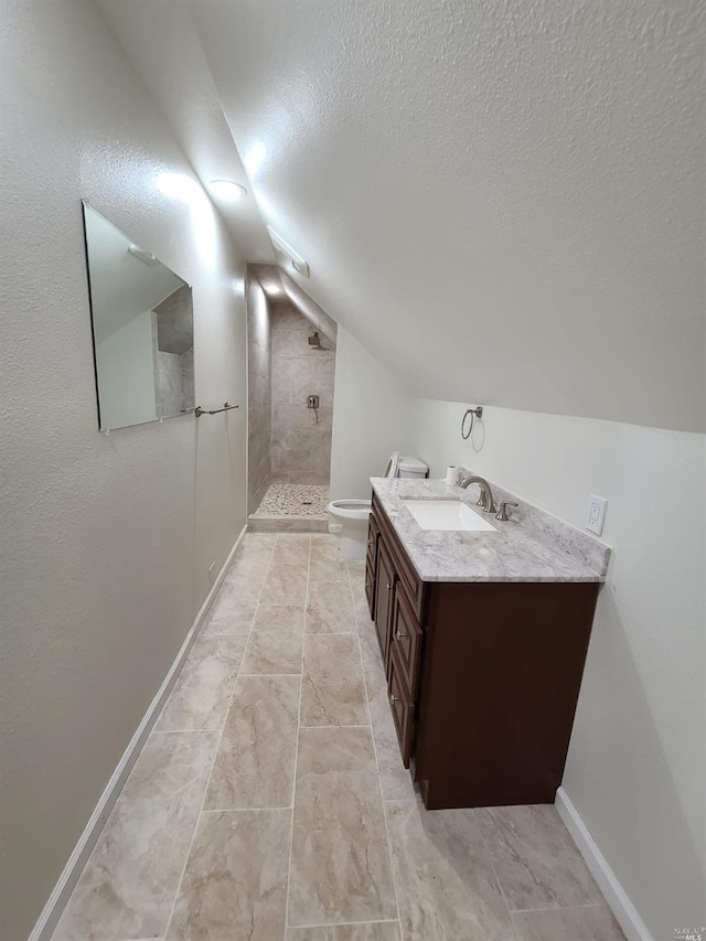 bathroom with tile floors, a textured ceiling, toilet, vanity, and a tile shower